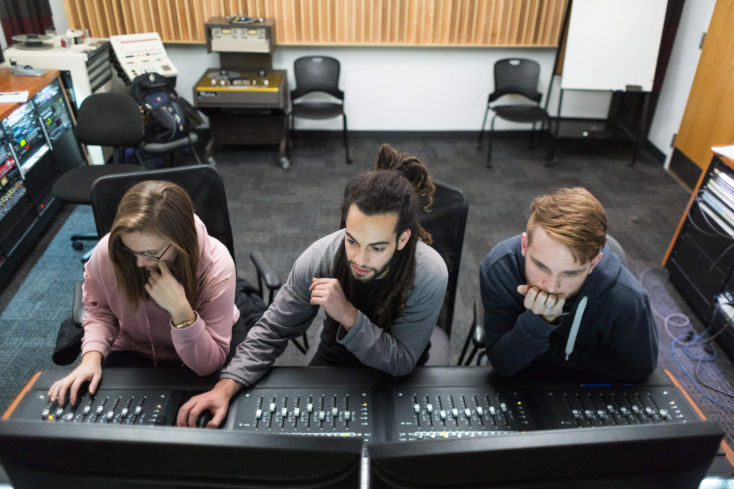 Audio arts and acoustics students at a sound board in our recording studio
