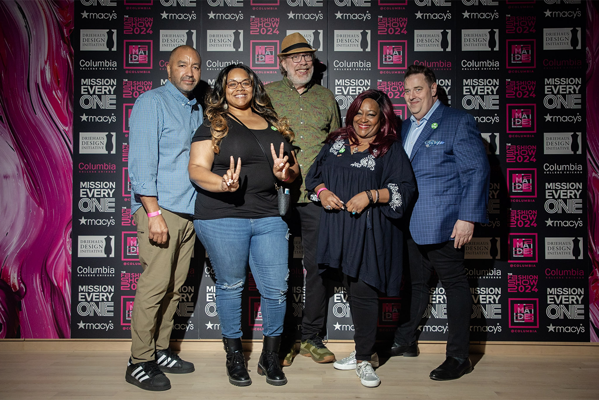 group photo in front of step-and-repeat signage with fashion show logos