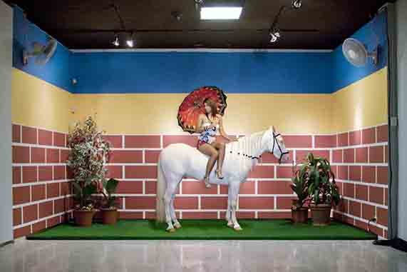 woman with umbrella riding horse in front of brick wall